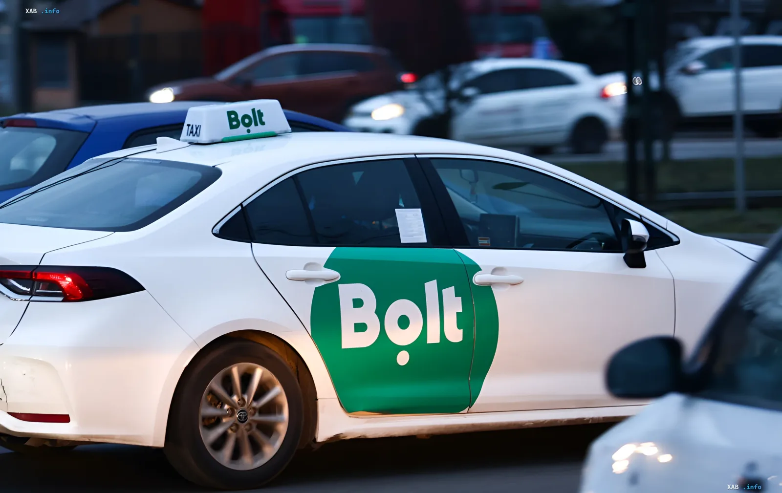 Weißes Bolt-Taxi mit Logo an Tür und Dach im Stadtverkehr – Illustration zur Nachricht über Preiserhöhungen bei Sturm und Alarm